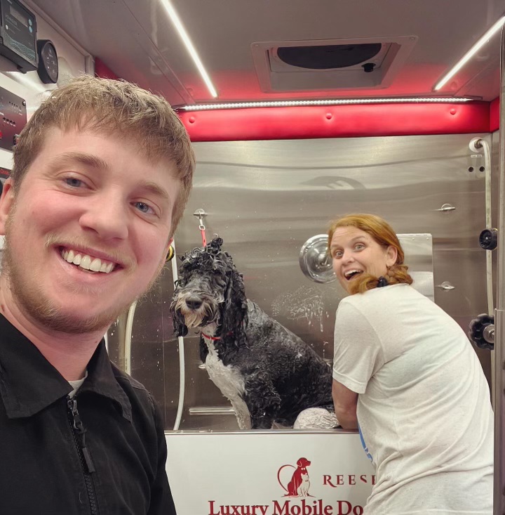 Ashleigh smiling with a dog during a grooming session